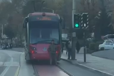 Seyir halindeki tramvayın arkasına oturarak yolculuk yapan çocuk, görenleri hayrete düşürdü