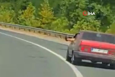 Ayaklarını camdan sarkıtarak trafiği tehlikeye attı
